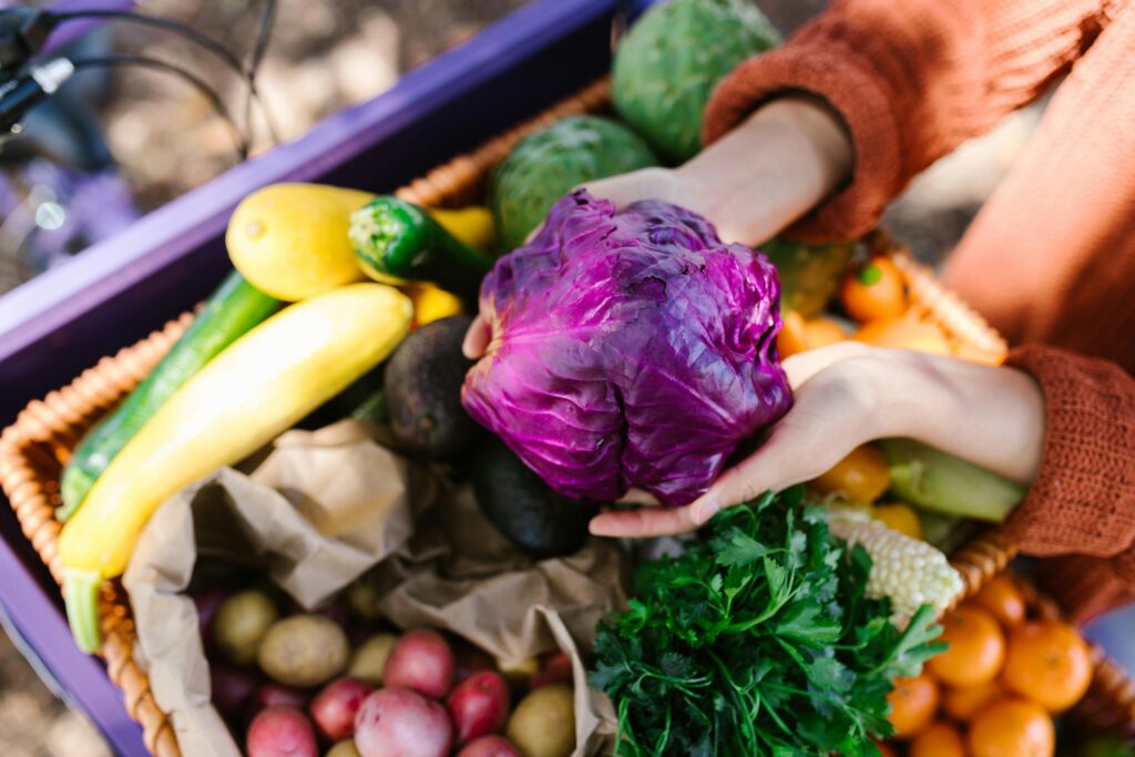 Holding a purple cabbage at the farmers market with bright veggies