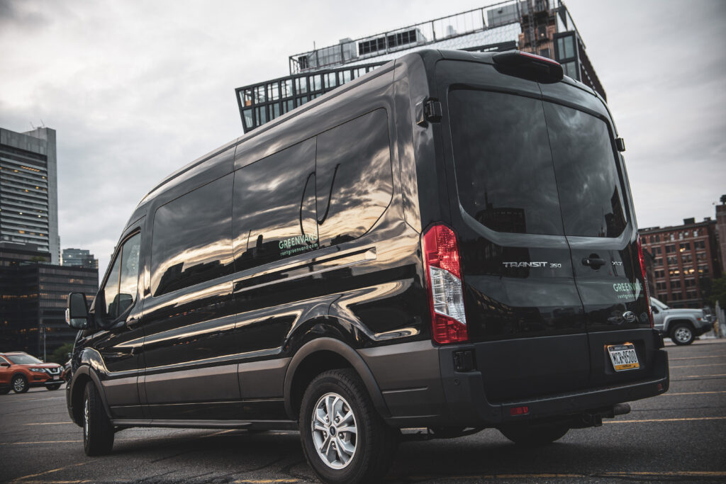 a black Ford Transit rental van in a parking lot