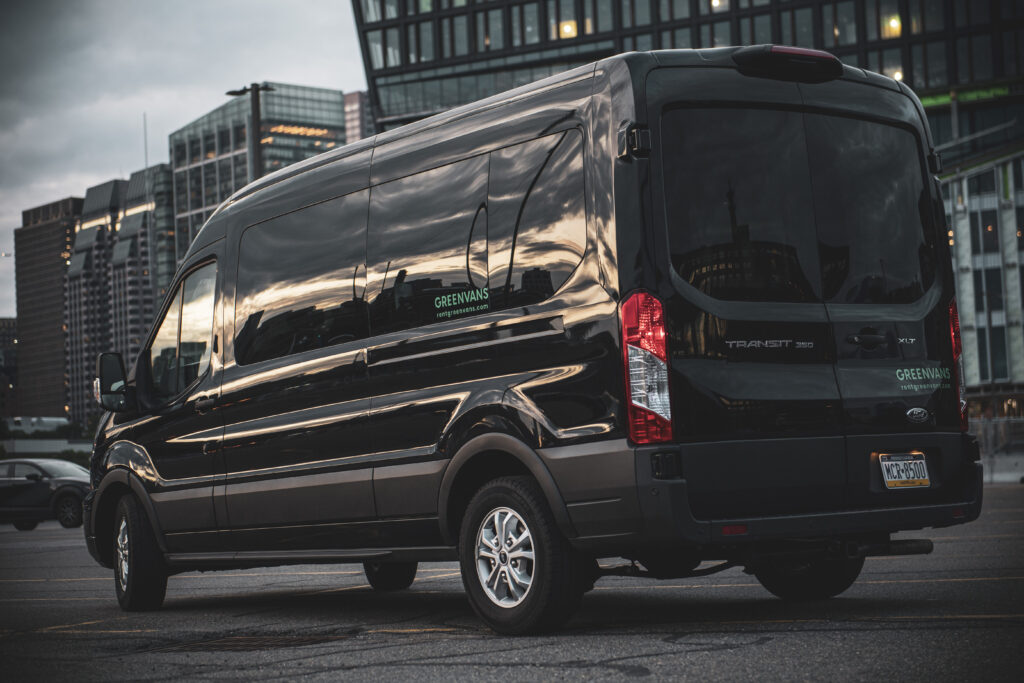 A black Ford transit van rental in a parking lot in front of a high-rise office building