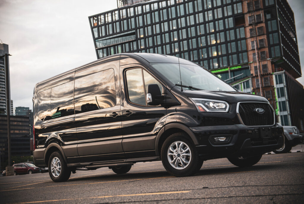 A Ford Transit rental van in front of a city building.