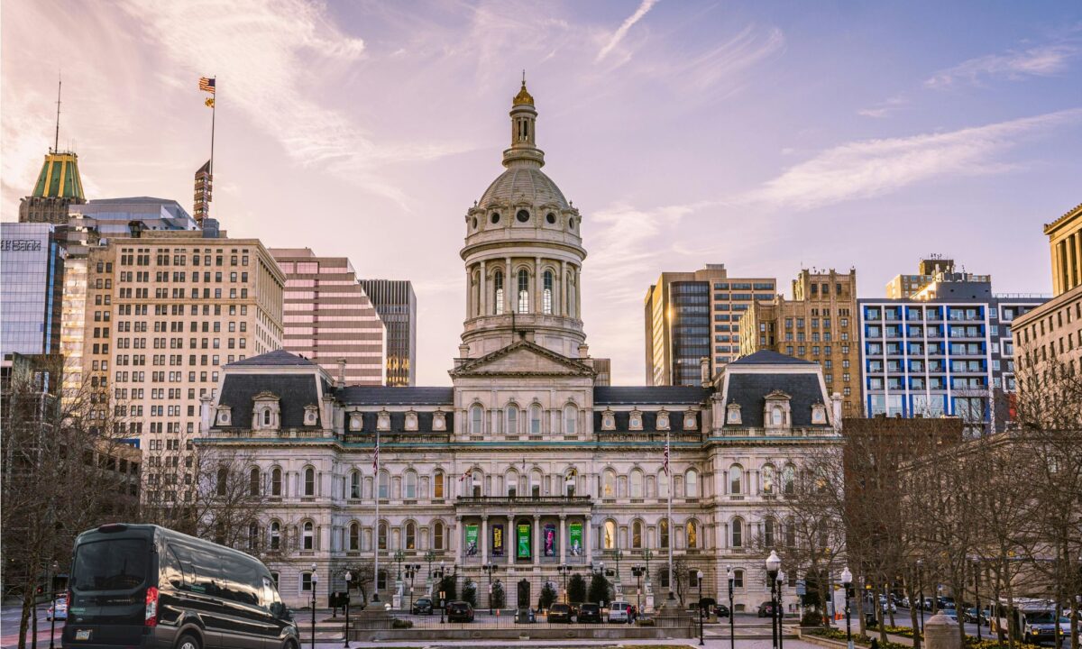 a Ford Transit passenger van in front of the Baltimore City Hall on a sunny day