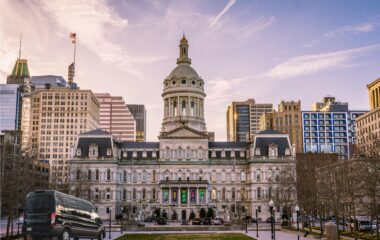 a Ford Transit passenger van in front of the Baltimore City Hall on a sunny day