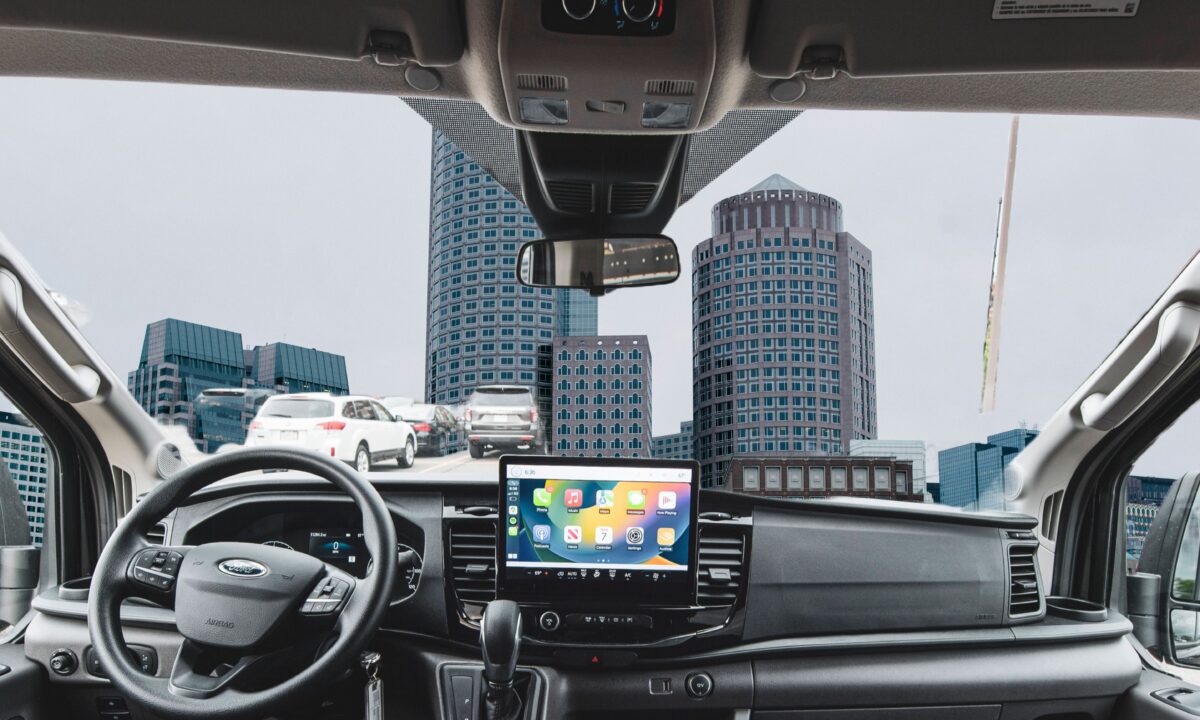 Interior dashboard of a Ford Transit passenger van with the Boston skyline through the windshield