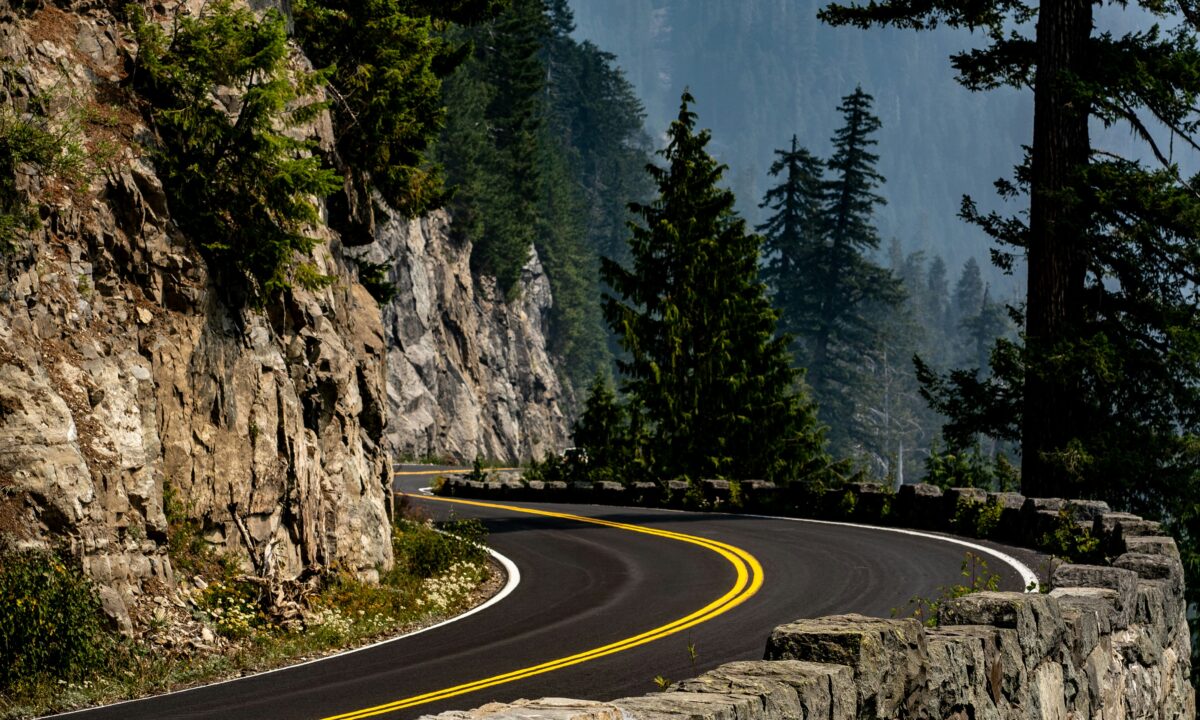 A winding road through a U.S. National Park with mountains and pine trees.