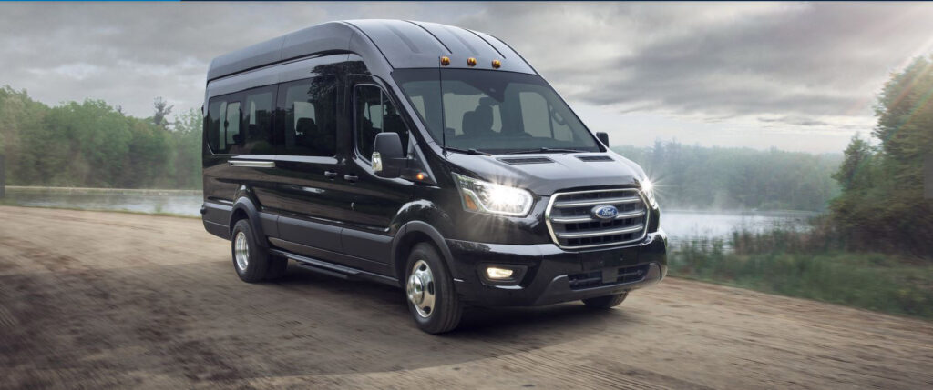 A Ford Transit passenger van driving through a National Park.