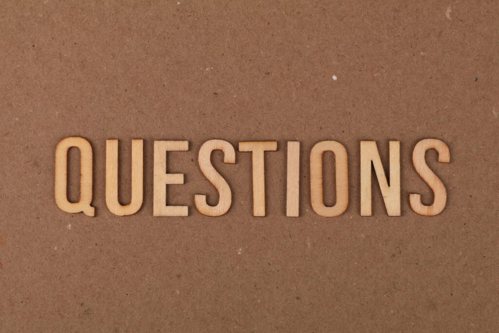 Brown board with the word QUESTIONS spelled in wooden letters