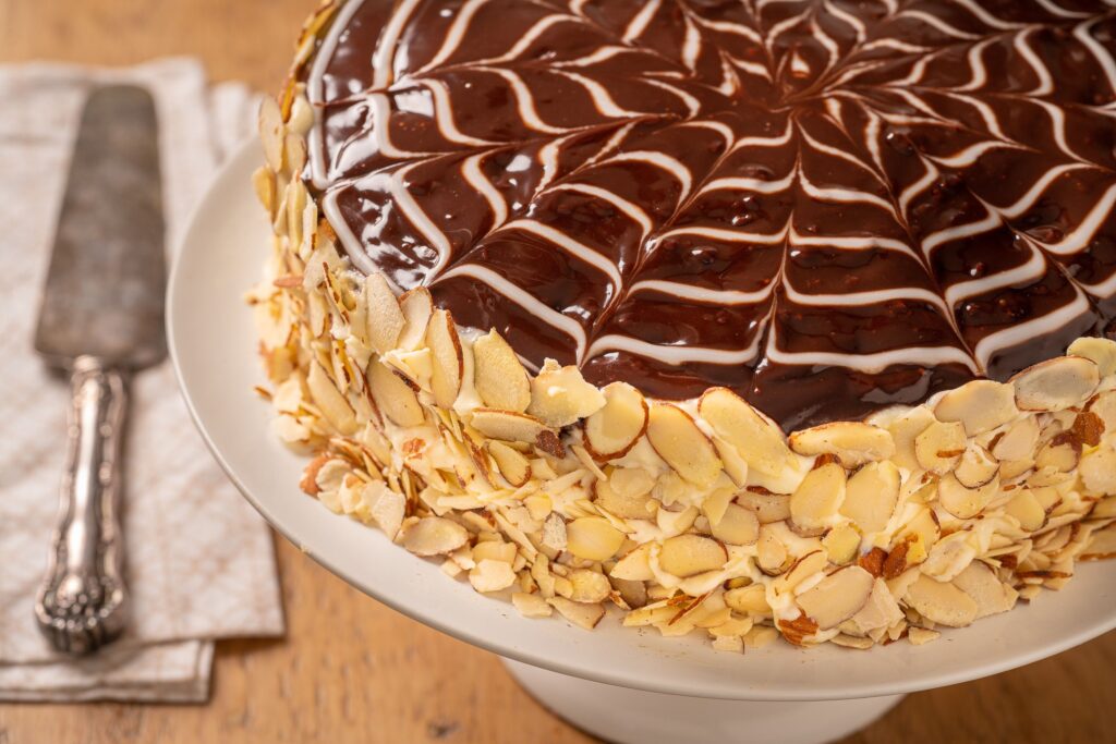 A Boston Cream pie on a serving plate with chocolate icing and a cake knife