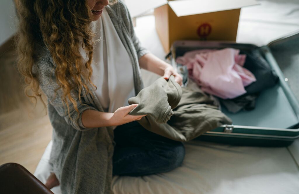 a woman packing a suitcase on her bed