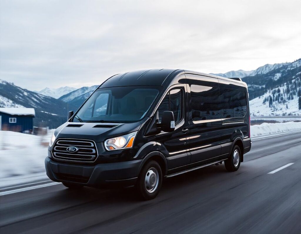 A Black Ford Transit passenger van driving in a mountainous area in the winter