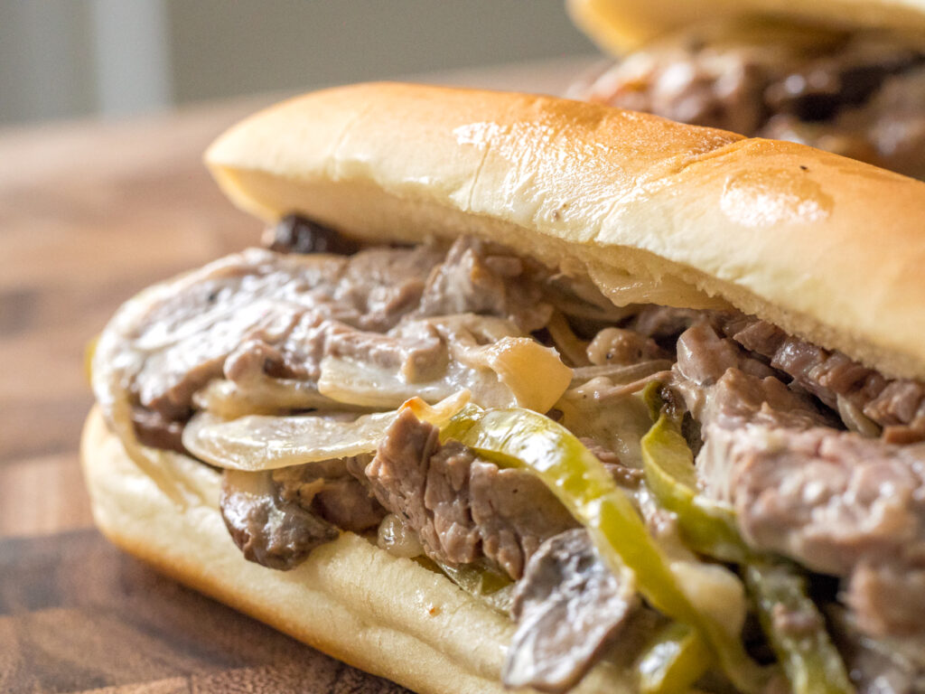 a juicy cheesteak with peppers and onions on a soft roll.