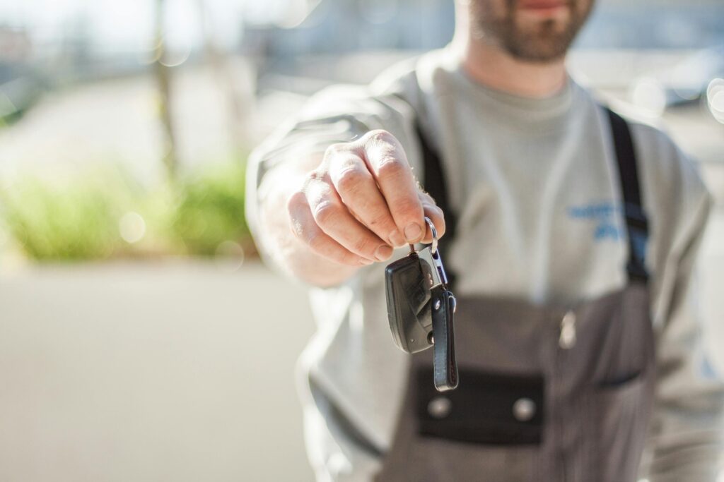 A man in overalls handing over a set of car keys.