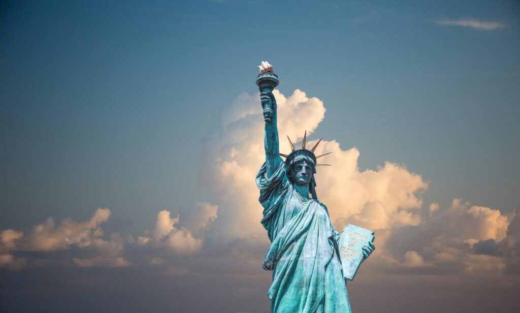 Statue of Liberty in front of a blue sky with puffy white clouds