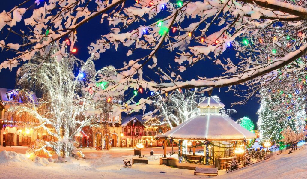 Leavenworth at night covered in snow with Christmas lights in the trees