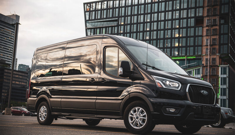 Greenvans black Ford Transit passenger van in front of an office building