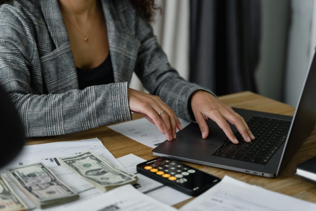 woman on laptop with calculator, cash, and paperwork